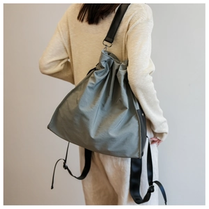Detail of sage green nylon shoulder bag with pleated texture and black fabric strap