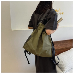 Detailed back view of a large olive green canvas crossbody bag on a female model