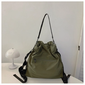 Detail of army green nylon drawstring bucket bag showing texture and front zipper pocket