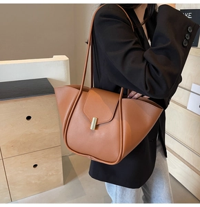 Détail d'un sac en cuir marron caramel avec boucle dorée et doubles bretelles d'épaule
