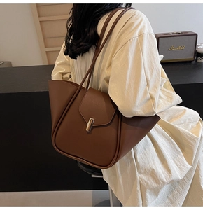 Détail d'un sac à épaule en cuir marron avec fermoir doré et design en forme d'ailes