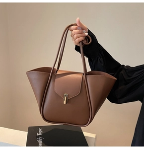 Détail d'un sac à main en cuir marron avec design ailé et fermoir métallique doré élégant