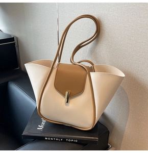 Détail du sac minimaliste en cuir crème avec bordure marron et boucle dorée