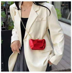 Chic red mirror finish clutch bag with gold chain strap on a white blazer outfit