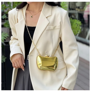 Close-up of polished gold metal hard shell evening clutch with a sleek chain strap