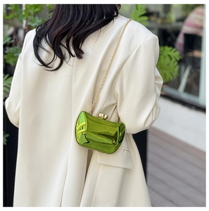 Detail of lime green metallic mirror evening bag with gold chain on white blazer