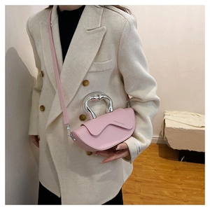 Détail du sac bandoulière rose clair avec une poignée métallique unique en forme de cœur