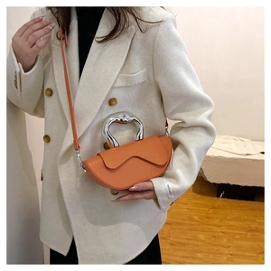 Détail du sac à main en cuir orange avec poignée en métal argenté et bandoulière