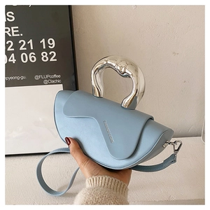 Détail du sac bandoulière bleu clair avec poignée en métal argenté et rabat ondulé