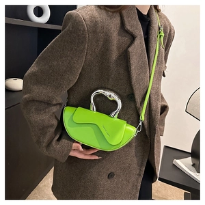 Détail du sac croissant vert citron avec poignée métallique sur blazer marron
