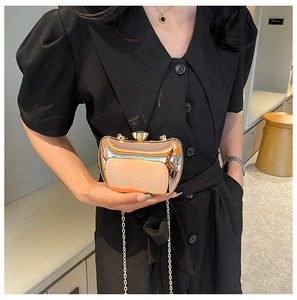 Close-up of golden metallic clutch bag with gemstone clasp and elegant chain strap