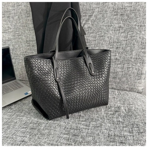 Dettaglio della borsa tote intrecciata nera che mostra la trama della pelle e l'intreccio