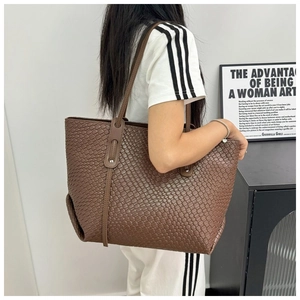 Dettaglio di una borsa tote marrone in pelle intrecciata indossata da una modella per stile