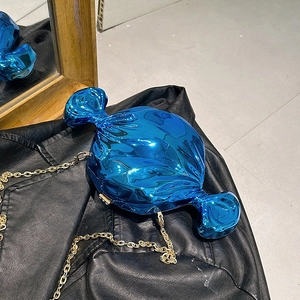 Chic blue metallic candy-shaped clutch with gold chain on a black leather jacket