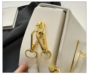 Detail of premium gold metal buckle and chain on white leather saddle shoulder bag