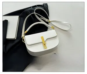 Close-up of white leather saddle bag with gold metal clasp and adjustable shoulder straps