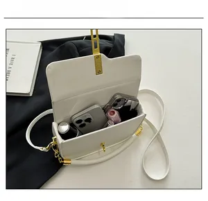 Internal capacity of white leather saddle bag showing two phones, lipstick and perfume