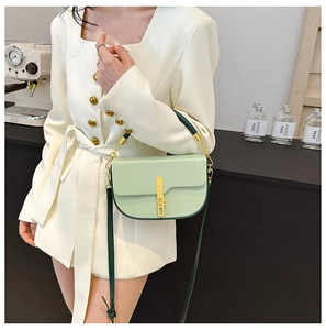Detail of light green saddle bag with gold metal buckle shown on a white dress