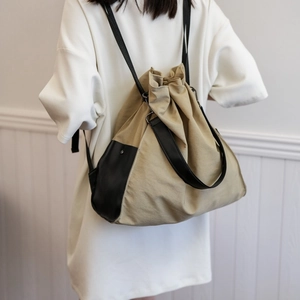 Minimalist khaki bucket shoulder bag with drawstring closure and black leather accents
