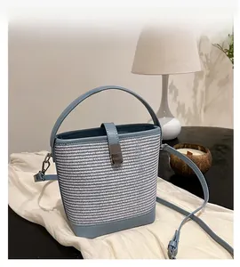 Dettaglio della borsa a secchiello intrecciata bianca e blu con tracolla in pelle e chiusura