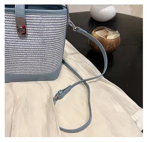 Dettaglio della trama in paglia blu e bianca con finiture in pelle azzurra e chiusura in metallo