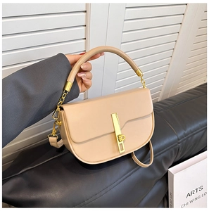 Close-up of beige leather saddle bag featuring a sleek vertical gold metal lock buckle