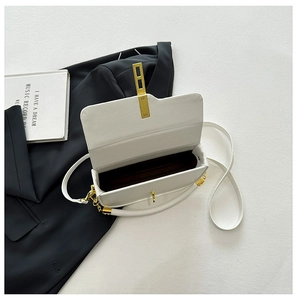 Detailed view of white leather saddle bag with golden flip lock and brown inner lining