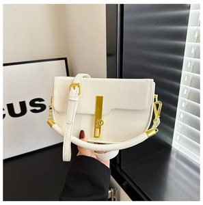 Detailed close-up of white saddle bag showing golden vertical metal clasp and smooth texture