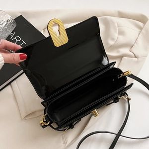 Sac à bandoulière minimaliste noir avec compartiments multiples et fermoir doré chic