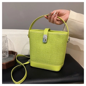 Dettaglio borsa a secchiello in paglia verde neon con trama intrecciata e chiusura a girello