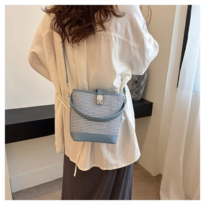 Vista posteriore di una borsa a secchiello intrecciata blu con chiusura d'argento su modella