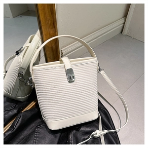 Dettaglio della borsa a secchiello bianca con texture intrecciata e chiusura in metallo