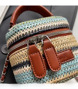 Close-up of smooth metal dual zippers and woven striped texture on a mini cylindrical bag