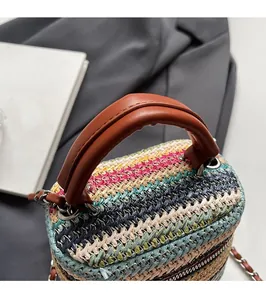 Detail of colorful woven straw bag featuring brown leather handle and silver hardware