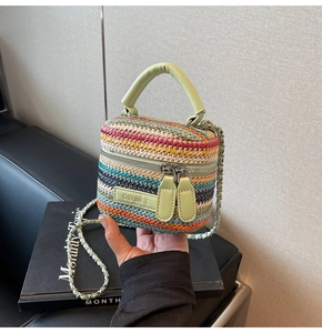 Detailed close-up of multi-colored striped woven mini bag with green leather handle