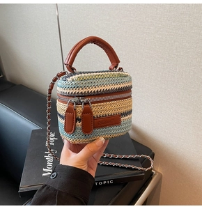 Detail of colorful striped woven mini bucket bag with leather handle and metal chain