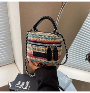 Detail of colorful woven mini box bag with black leather handle and metal chain strap