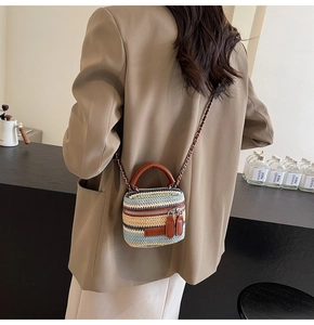 Detail of colorful woven straw mini bag with brown leather handles and chain strap