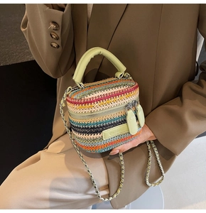 Detail of colorful woven mini box bag with green leather handle and chain strap