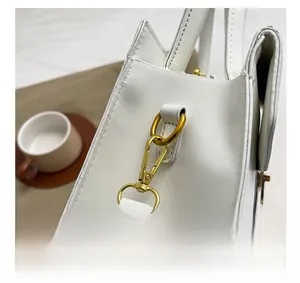 Gros plan détaillé sur les boucles dorées et la fermeture d'un sac à main blanc chic