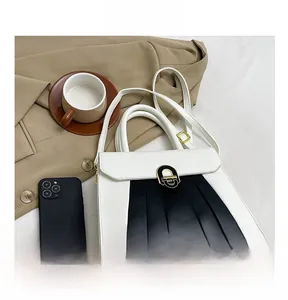 Détails d'un sac à main bicolore avec boucle dorée et clous de protection sur un costume