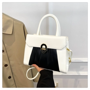 Détail d'un sac à main bicolore avec fermoir doré et design plissé élégant pour femmes