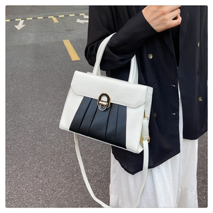 Détail du sac à main bicolore en cuir blanc et noir avec fermoir doré et design plissé