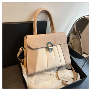 Détail d'un sac à bandoulière plissé beige avec rabat dans un emballage cadeau de luxe