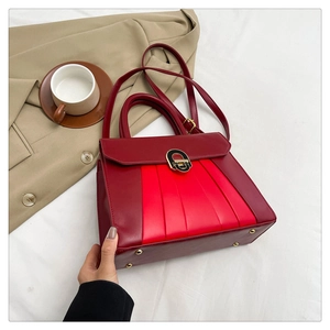Détail du sac à main bicolore rouge avec fermoir doré, poignée et clous de protection