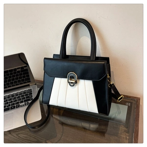 Détail d'un sac à main noir et blanc avec boucle en métal dans un décor de bureau chic