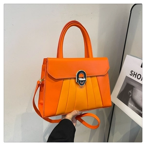 Détail d'un sac à main orange plissé avec fermoir ovale en métal argenté brillant
