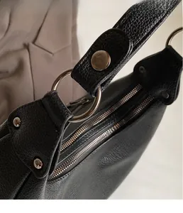 Detail of silver hardware ring and pebbled leather texture on black shoulder bag