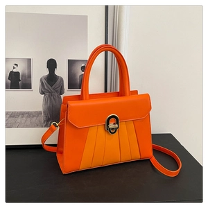 Détail du sac à main trapèze orange avec fermoir rotatif doré et texture plissée