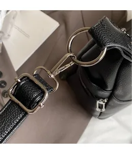 Detail of silver metal swivel hook and adjustable buckle on black lychee leather bag